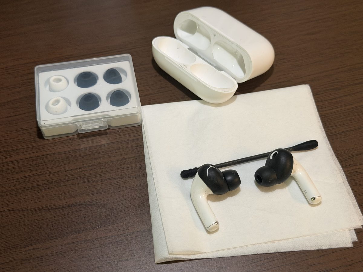 使用中のAirPods Pro本体、ケース、スペアのイヤーチップを、洗浄前の状態のまま机の上に並べて撮った写真