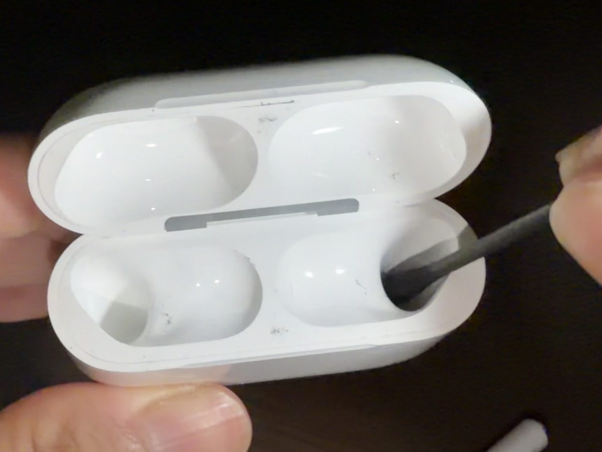 アルコールを含ませた綿棒でケースの充電口周辺と、AirPodsが収まる内側のくぼみを拭いている写真